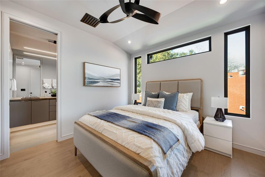 Owner's Suite Bed 1 featuring lofted ceiling, light wood floors, and ensuite bathroom