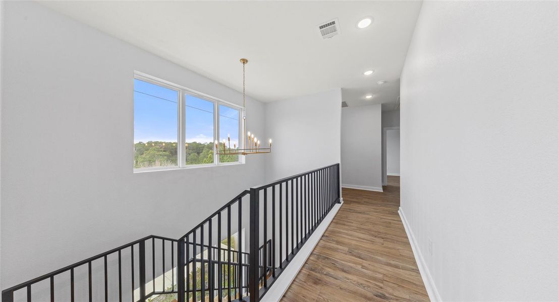 Hallway with a chandelier, wood finished floors, recessed lighting, and an upstairs landing