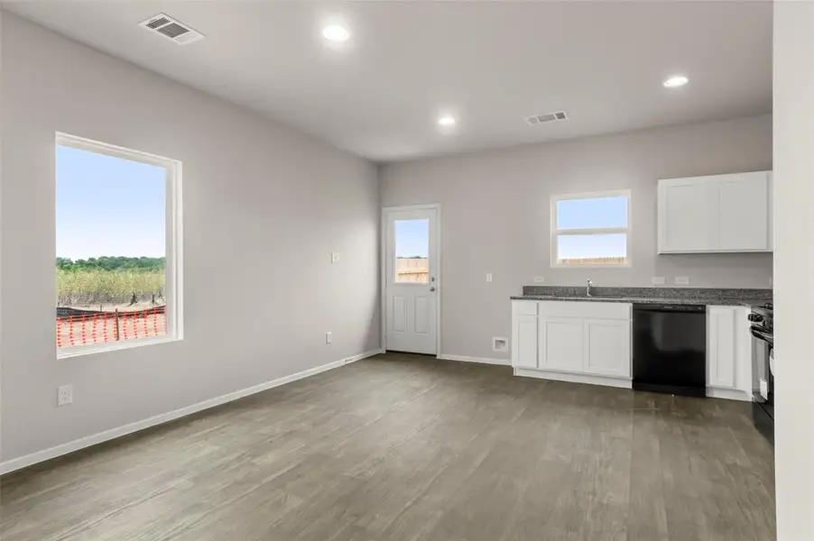 Kitchen with black appliances, white cabinetry, wood finished floors, recessed lighting, and dark stone counters