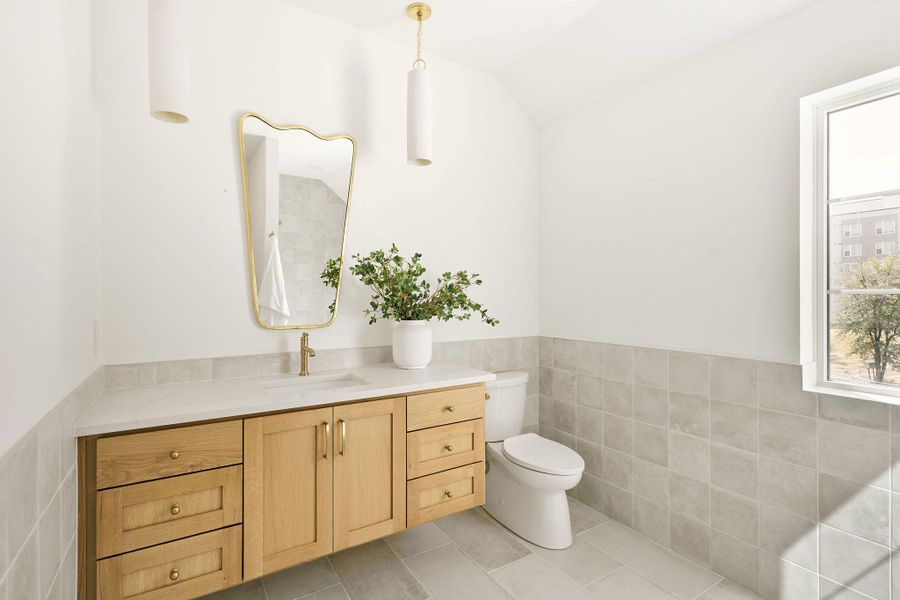 Bathroom with vanity, healthy amount of natural light, tile walls, a wainscoted wall, and tile patterned flooring Bathroom with vanity, healthy amount of natural light, tile walls, a wainscoted wall, and tile patterned flooring