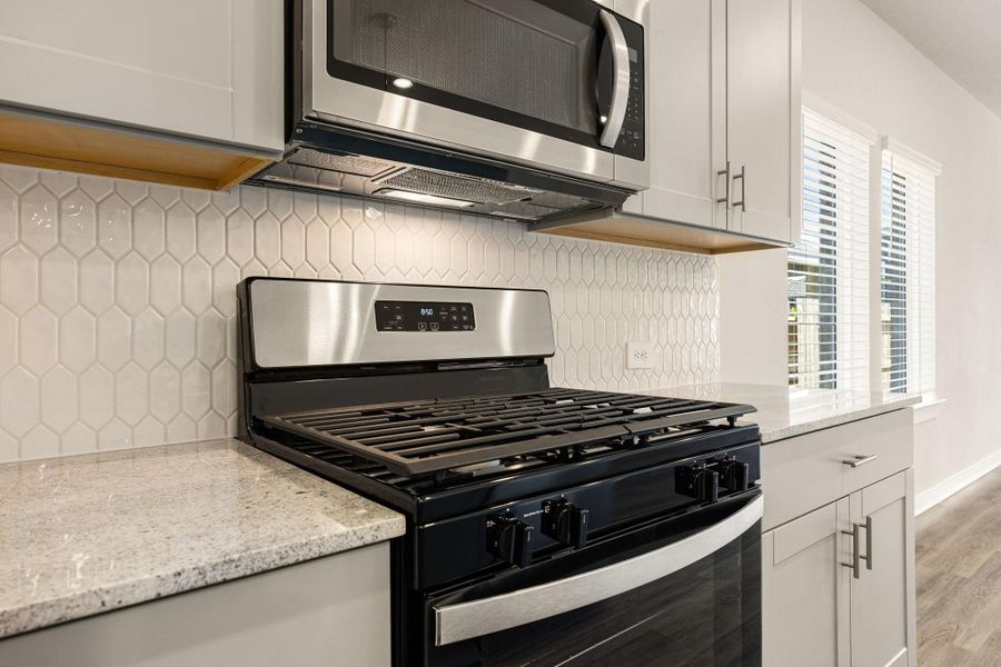 Featured here is the gas range and microwave. Not to mention the beautiful quartz countertop and modern backsplash! Featured here is the gas range and microwave. Not to mention the beautiful quartz countertop and modern backsplash!