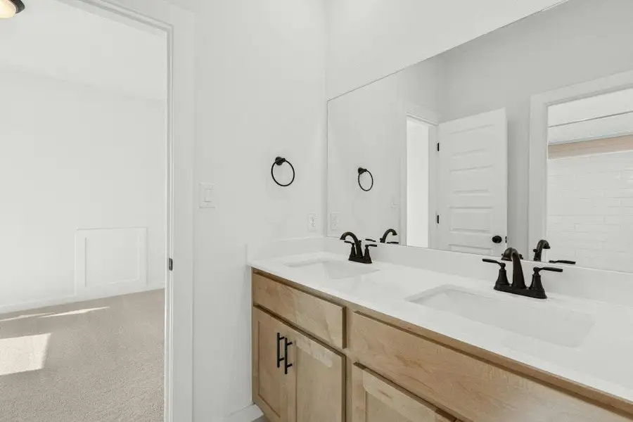 Bathroom with double vanity and light carpet