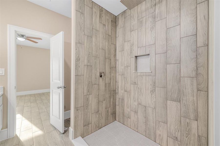 Bathroom featuring a tile shower and ceiling fan