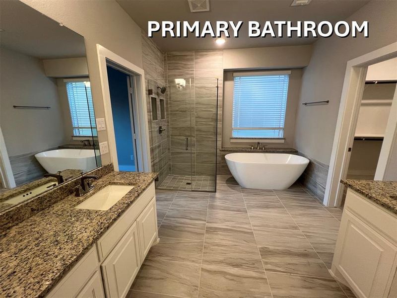 Spacious bathroom featuring a freestanding soaking tub, a large walk-in shower with glass enclosure, dual vanity with granite countertops, and wood-look tile flooring Spacious bathroom featuring a freestanding soaking tub, a large walk-in shower with glass enclosure, dual vanity with granite countertops, and wood-look tile flooring