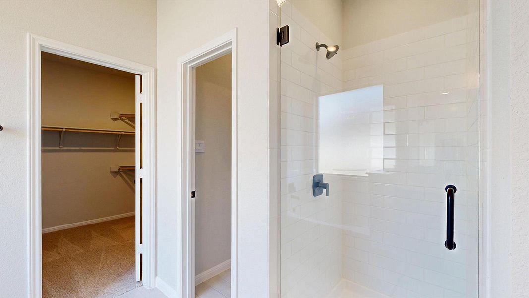 Full bath featuring a walk in closet, a shower stall, and light colored carpet Full bath featuring a walk in closet, a shower stall, and light colored carpet