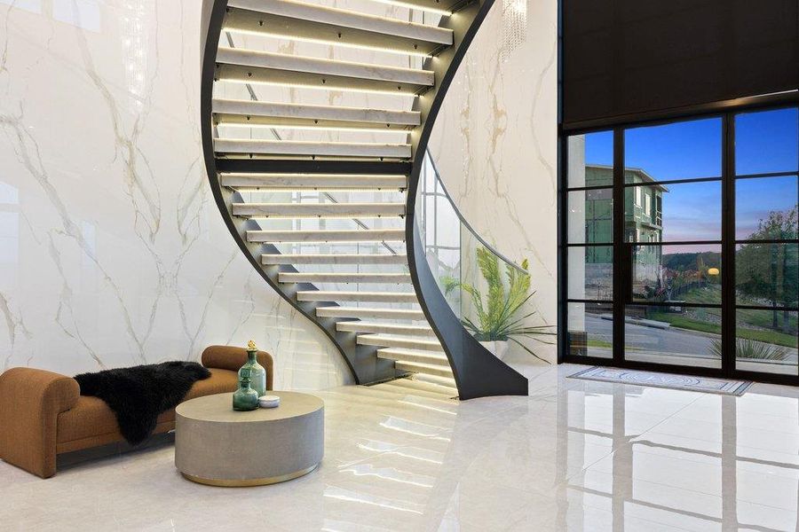 A grand entrance welcomes you with a floating spiral staircase, gleaming tile floors, and a dramatic wall of windows.