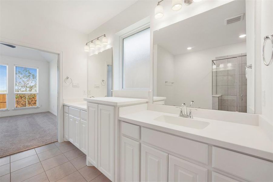 Bathroom with vanity, tile patterned flooring, and a tile shower