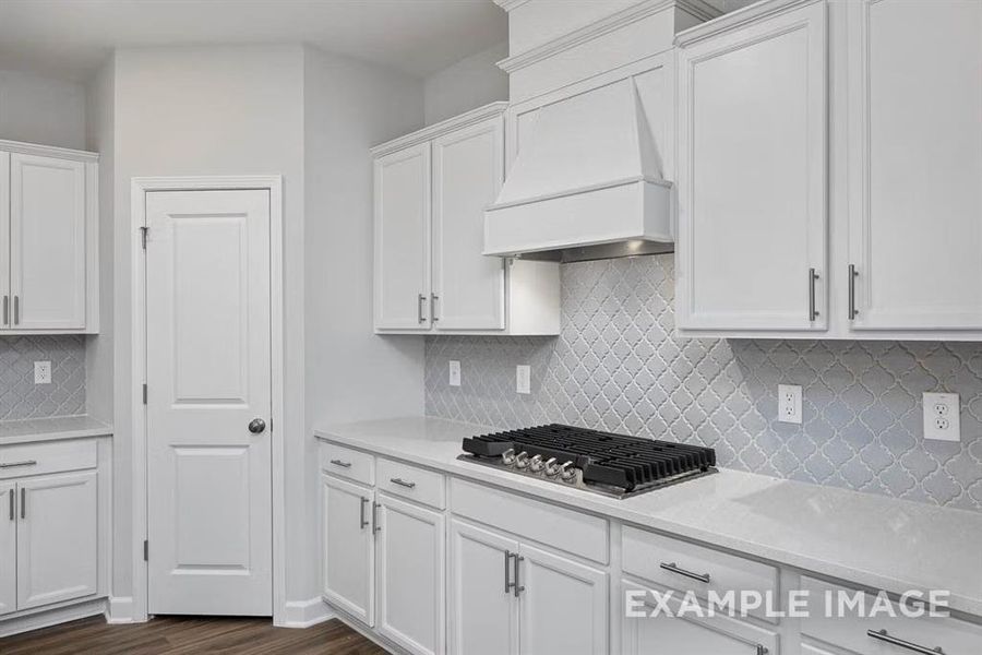 Kitchen with tasteful backsplash, white cabinets, stainless steel gas cooktop, dark wood-type flooring, and custom range hood