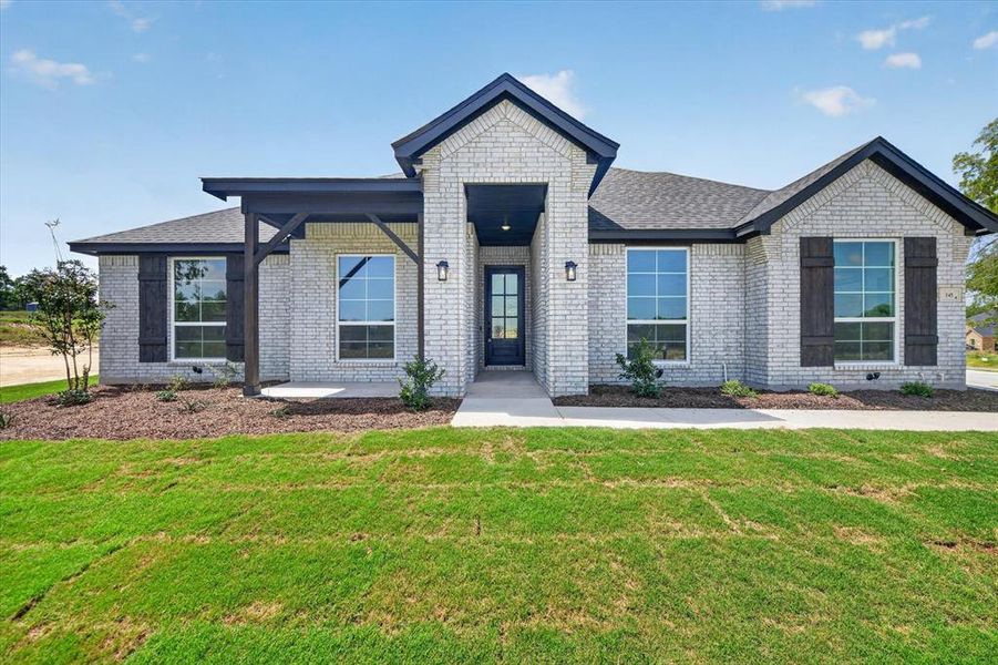 Brick exterior with dark trim accents, covered entry, front door with glass panels, and decorative window shutters Brick exterior with dark trim accents, covered entry, front door with glass panels, and decorative window shutters