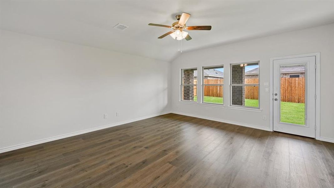 Spacious interior featuring wood-finish flooring, white baseboards, and a ceiling fan with integrated lighting Spacious interior featuring wood-finish flooring, white baseboards, and a ceiling fan with integrated lighting