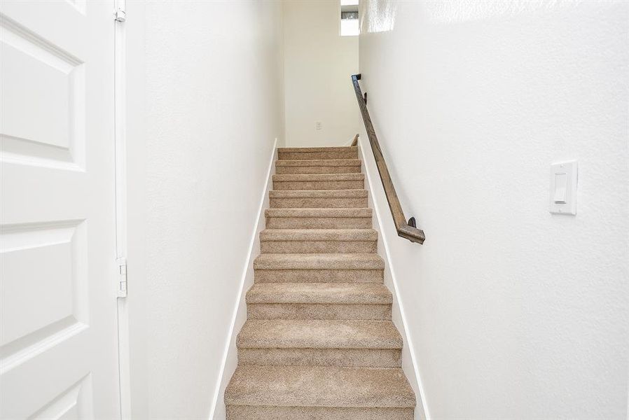 Plush carpeted stairs lead to the second level, offering a cozy and quiet transition between spaces