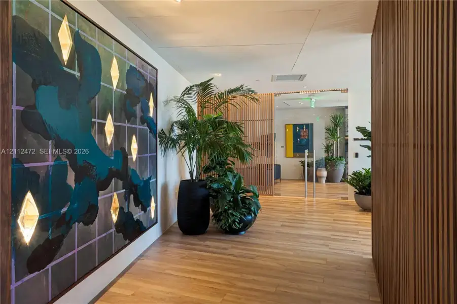 Interior lobby featuring wood-finish flooring, vertical wood-slat wall paneling, and recessed lighting