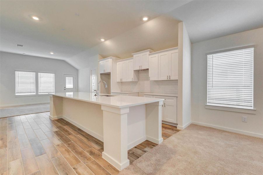The kitchen features a large island with a sleek countertop, white cabinetry, subway tile backsplash, and warm wood-look tile flooring. Open to the living and dining areas, this bright space offers both style and function with plenty of room for meal prep, casual dining, and gathering. The kitchen features a large island with a sleek countertop, white cabinetry, subway tile backsplash, and warm wood-look tile flooring. Open to the living and dining areas, this bright space offers both style and function with plenty of room for meal prep, casual dining, and gathering.