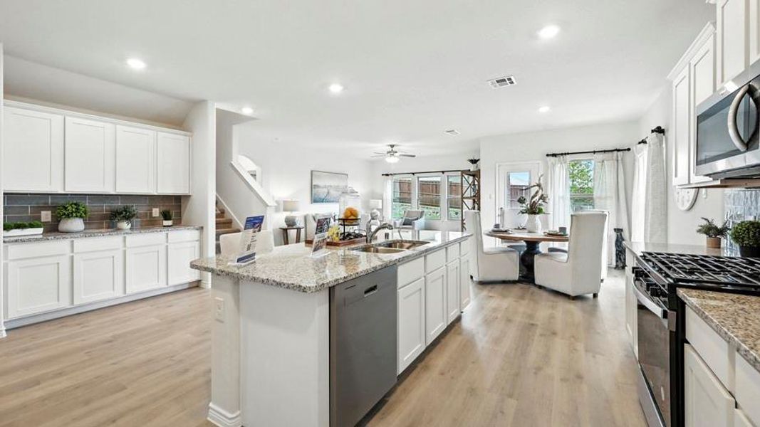 The kitchen features white cabinetry, granite countertops, a gas range, and a stainless steel dishwasher