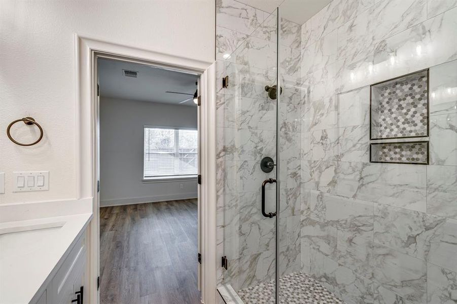 Bathroom featuring visible vents, wood finished floors, vanity, and a marble finish shower Bathroom featuring visible vents, wood finished floors, vanity, and a marble finish shower