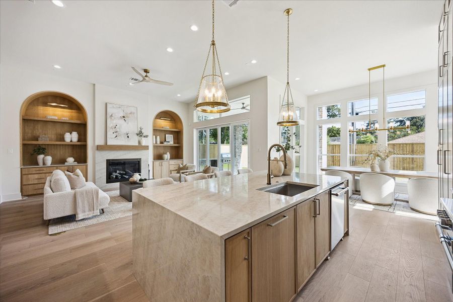 The custom white oak island takes center stage with a prep sink, bar seating and flush solid brass pop-up electrical outlets that keep the surface clean and functional. Gorgeous Visual Comfort fixtures overhead add a polished finishing touch, making this an easy place to prep, pour, serve and gather.