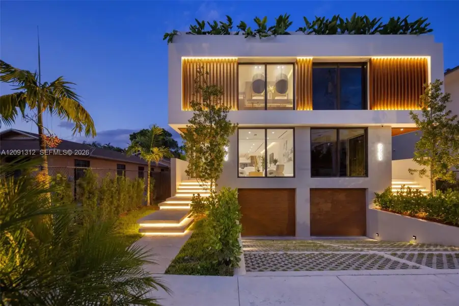 Modern two-story architectural exterior featuring clean lines, rhythmic vertical wood-slat screening, large-scale glass windows, integrated staircase lighting, and a permeable concrete paver driveway Modern two-story architectural exterior featuring clean lines, rhythmic vertical wood-slat screening, large-scale glass windows, integrated staircase lighting, and a permeable concrete paver driveway