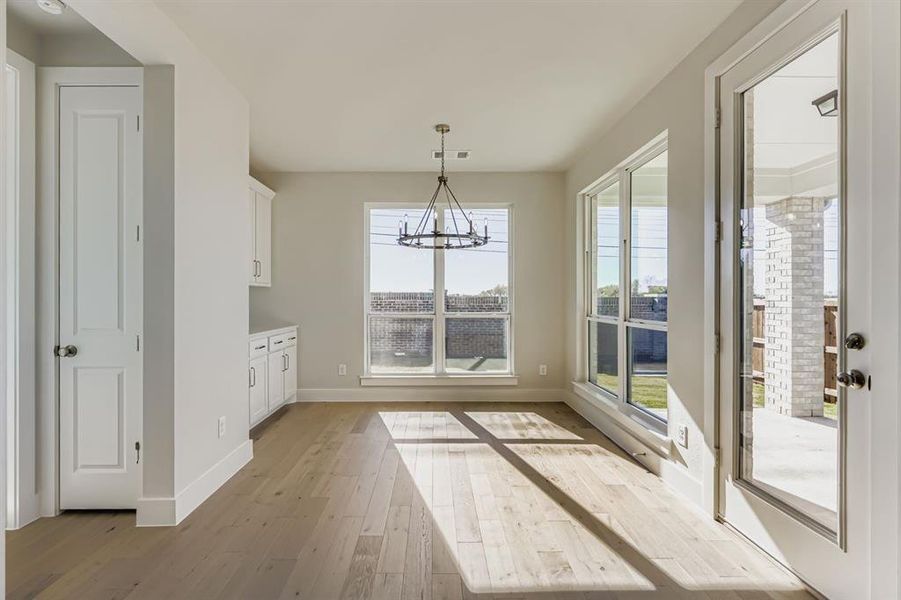 Unfurnished dining area featuring a chandelier and light wood-style flooring