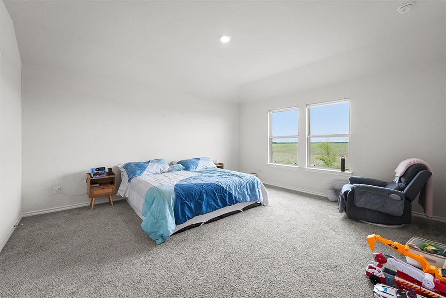 Spacious room featuring light gray carpet flooring, white walls, and two large windows offering abundant natural light and an expansive outdoor backdrop