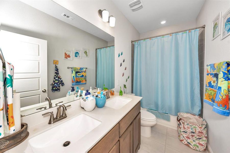 Full bathroom with toilet, shower / bath combo with shower curtain, vanity, and tile patterned flooring