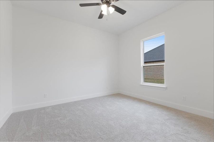 Carpeted empty room featuring ceiling fan and baseboards