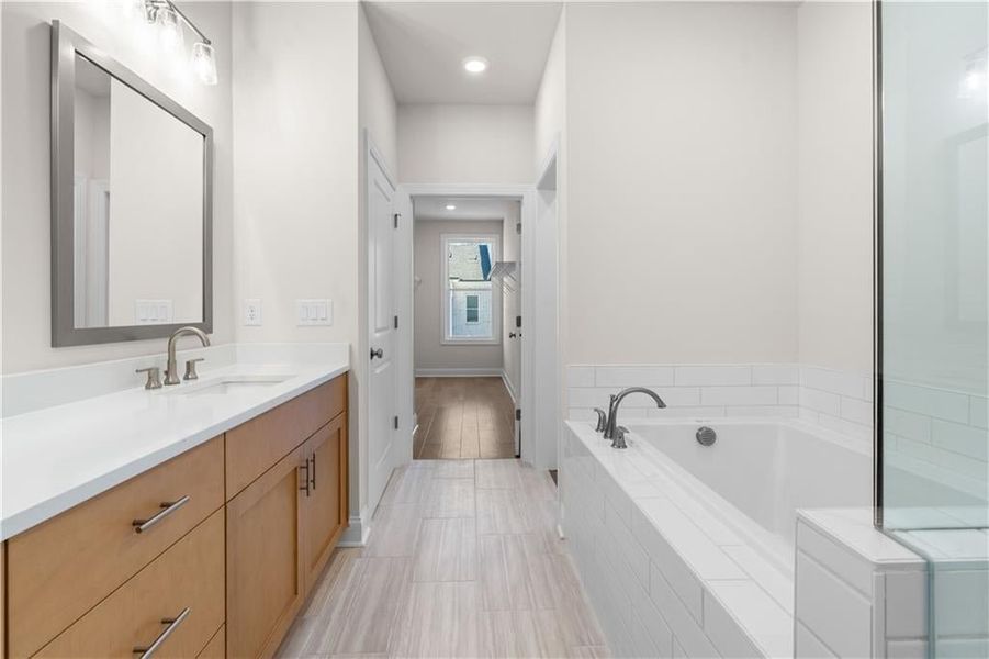 Bathroom with vanity, a bath, and recessed lighting