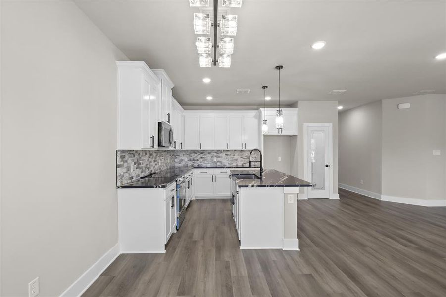 Kitchen with a kitchen island, pendant lighting, tasteful backsplash, white cabinetry, and sink