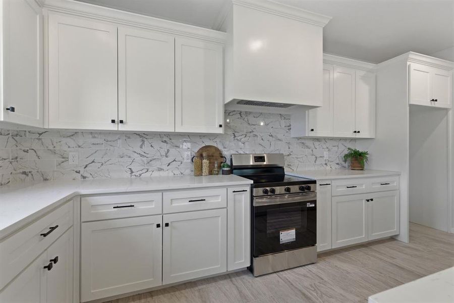 Kitchen with electric stove, white cabinetry, tasteful backsplash, and light stone counters Kitchen with electric stove, white cabinetry, tasteful backsplash, and light stone counters