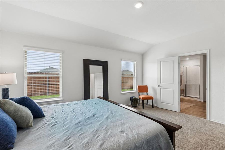 Carpeted bedroom with vaulted ceiling, recessed lighting, and ensuite bath Carpeted bedroom with vaulted ceiling, recessed lighting, and ensuite bath
