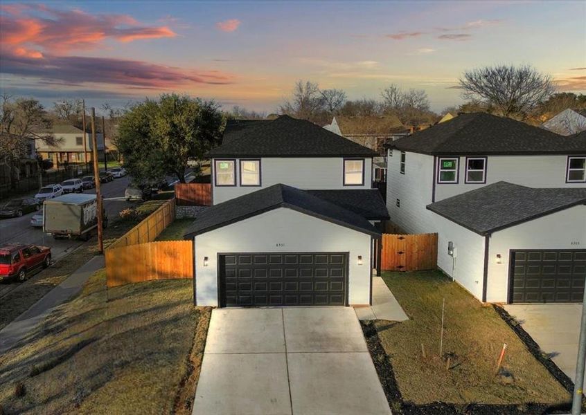 View of front of home with a garage and a yard