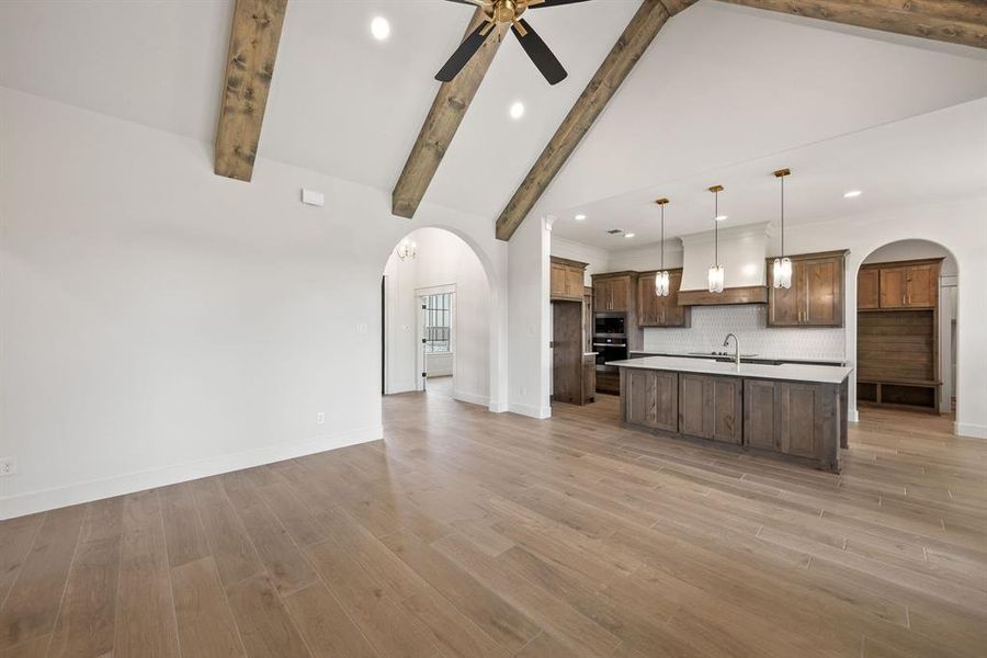 Open-concept living area featuring vaulted ceilings with exposed wood beams and wood-finish flooring
