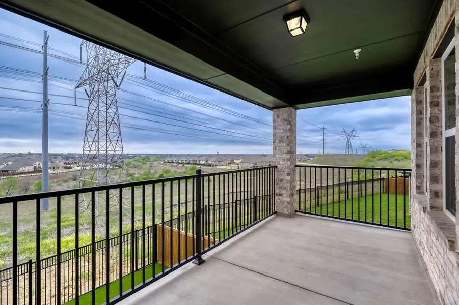 Covered balcony featuring concrete flooring and a black metal railing