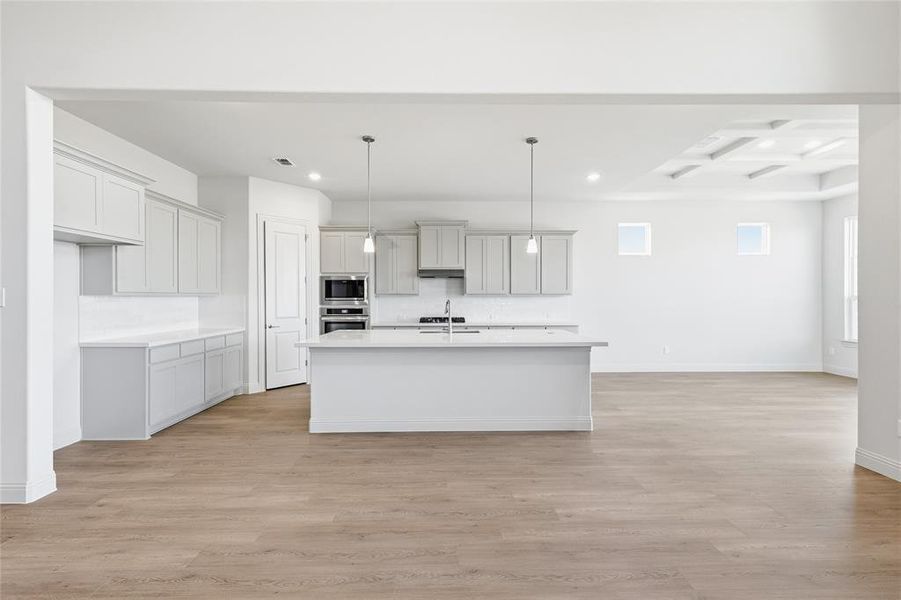 Kitchen with pendant lighting, light wood-style floors, recessed lighting, appliances with stainless steel finishes, and a center island with sink Kitchen with pendant lighting, light wood-style floors, recessed lighting, appliances with stainless steel finishes, and a center island with sink