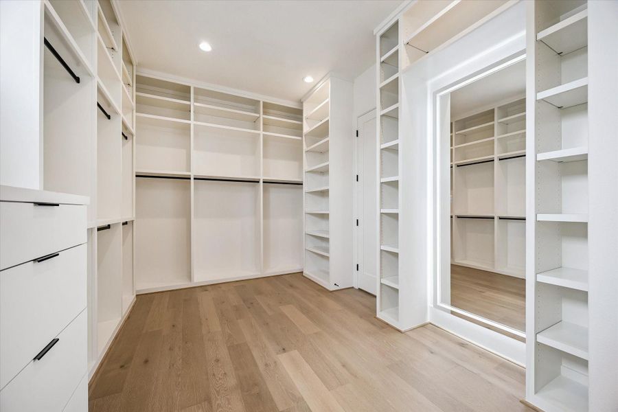 Spacious walk-in primary closet wth custom built-ins and a full length mirror. Spacious walk-in primary closet wth custom built-ins and a full length mirror.