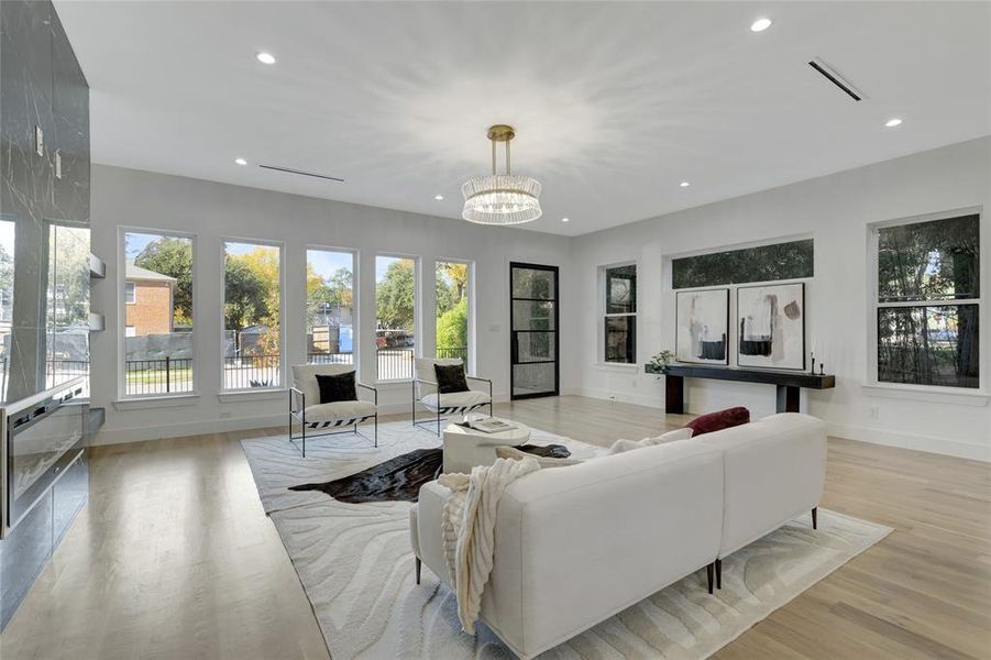 Living room featuring light wood-type flooring, an inviting chandelier, and a healthy amount of sunlight. Furniture is for staging only