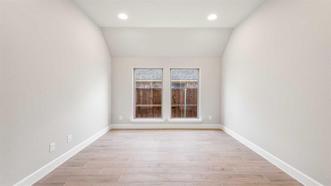 Empty room with light hardwood / wood-style flooring and vaulted ceiling