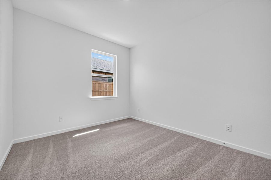 This cozy bedroom features soft carpeting and a bright window, creating a comfortable and inviting retreat.