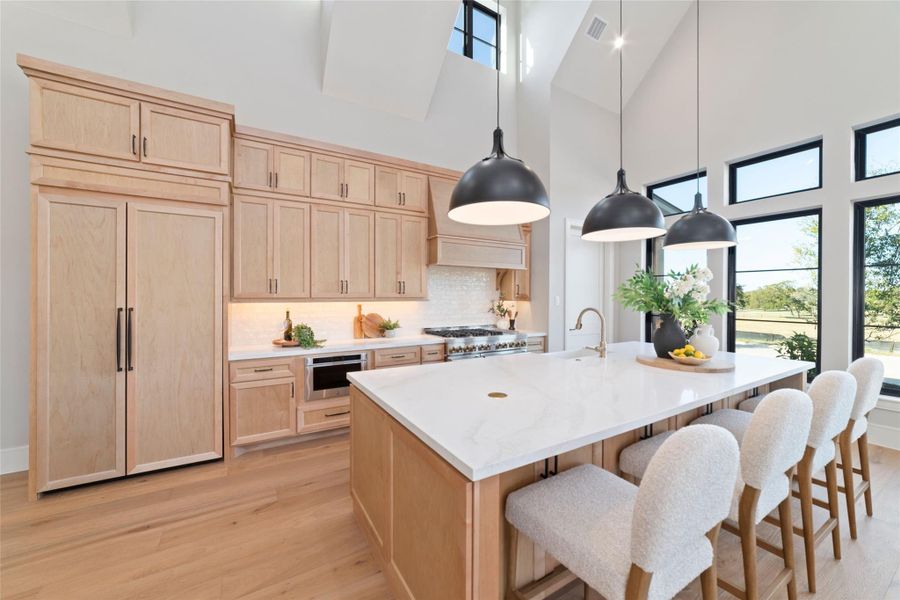 The gourmet kitchen is fully loaded with a built in refrigerator, stainless steal JenAir appliances, large quartz countertop island, soft-closed cabinetry,  and spacious walk in pantry.