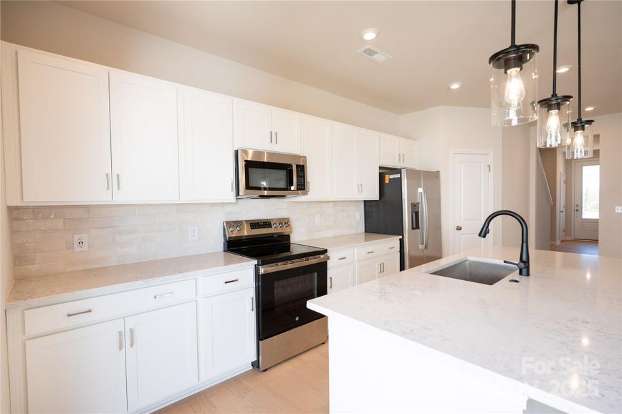 Quartz countertops and designer backsplash paired with matte black details.