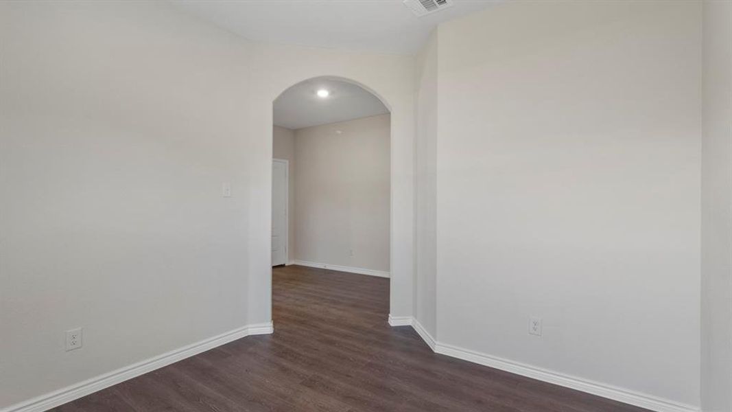 Spare room featuring arched walkways and dark wood-style floors Spare room featuring arched walkways and dark wood-style floors