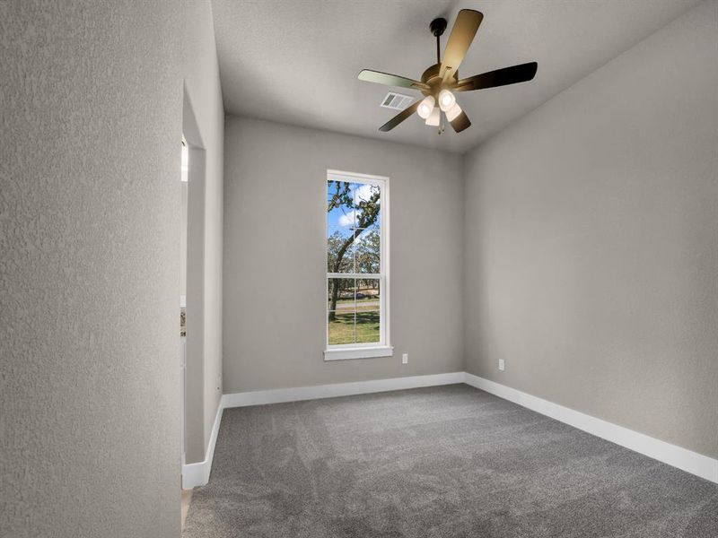 Spare room featuring a textured wall, light carpet, and a ceiling fan
