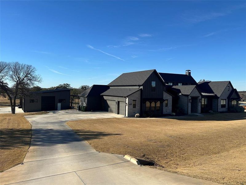Modern farmhouse style home with a garage, concrete driveway, an outbuilding, and board and batten siding Modern farmhouse style home with a garage, concrete driveway, an outbuilding, and board and batten siding