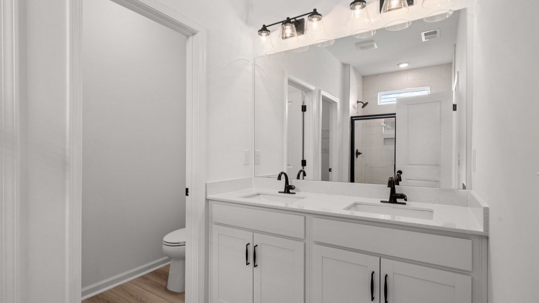 The spa-like primary bath features dual vanities and quartz countertops
