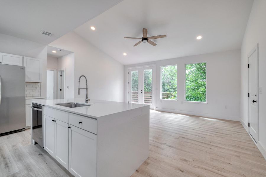 A sleek island kitchen flows seamlessly into a bright living space with direct outdoor access. A sleek island kitchen flows seamlessly into a bright living space with direct outdoor access.