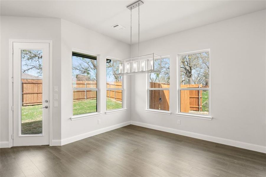 Unfurnished dining area with dark wood-style flooring, baseboards, and plenty of natural light Unfurnished dining area with dark wood-style flooring, baseboards, and plenty of natural light