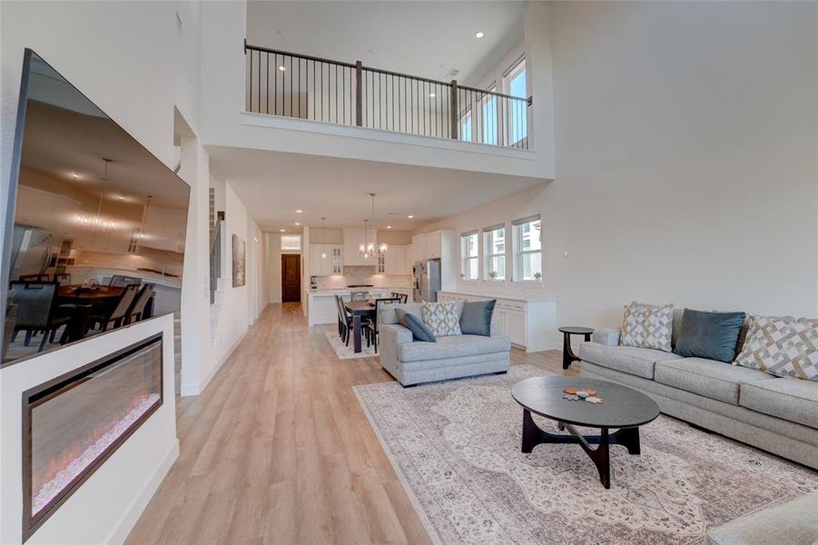 Living room featuring a chandelier, light wood-style floors, a towering ceiling, and recessed lighting