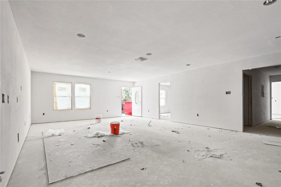 The property features a spacious room with white walls, recessed lighting, and two windows providing natural light