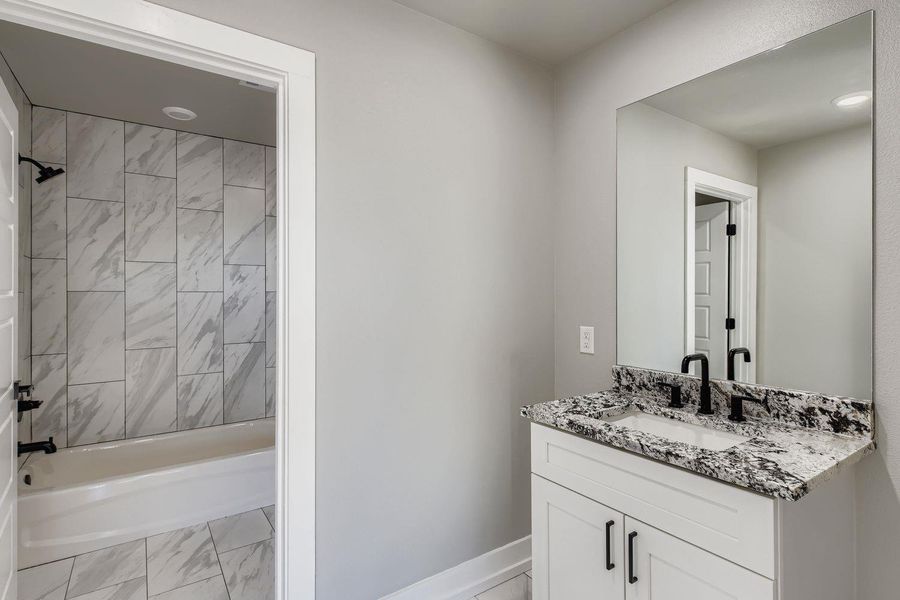 Bathroom featuring shower / bath combination, vanity, and light marble finish floors