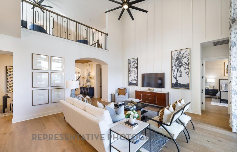 Living area featuring arched walkways, a high ceiling, ceiling fan, and light wood-type flooring