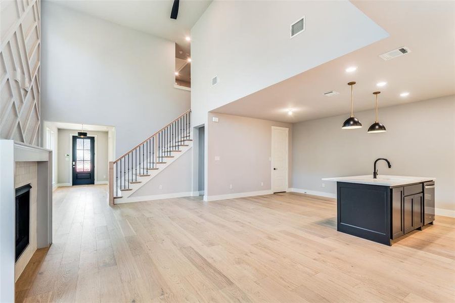 Unfurnished living room featuring a high ceiling, light wood-type flooring, and wine cooler